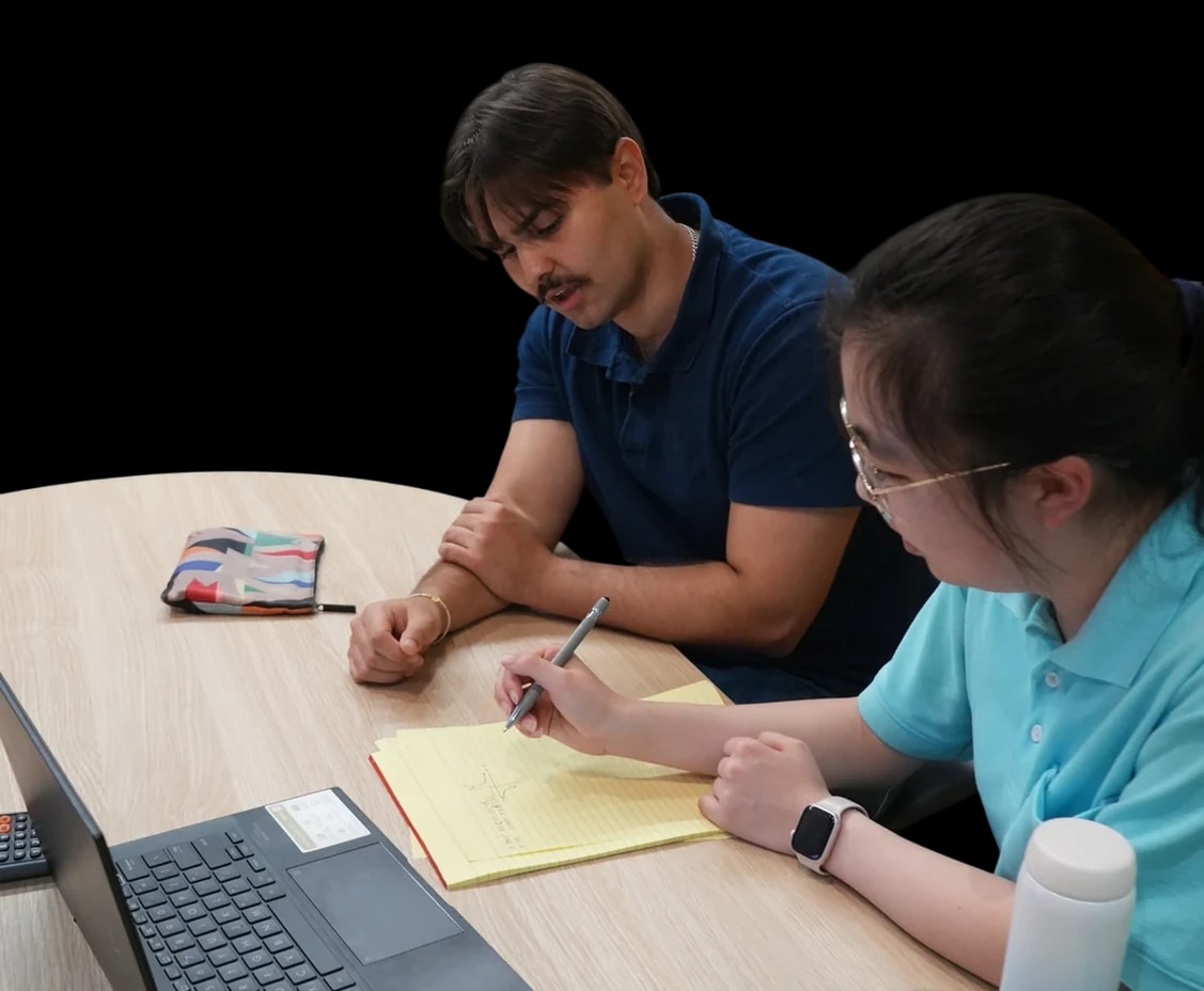 A tutor and a student working together at a table, at home and in a library